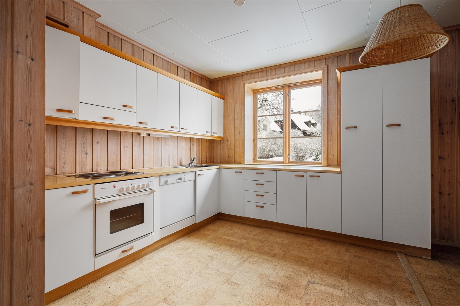 Kjøkkeninnredning av eldre dato med glatte fronter og belysning under overskap Galleribilde