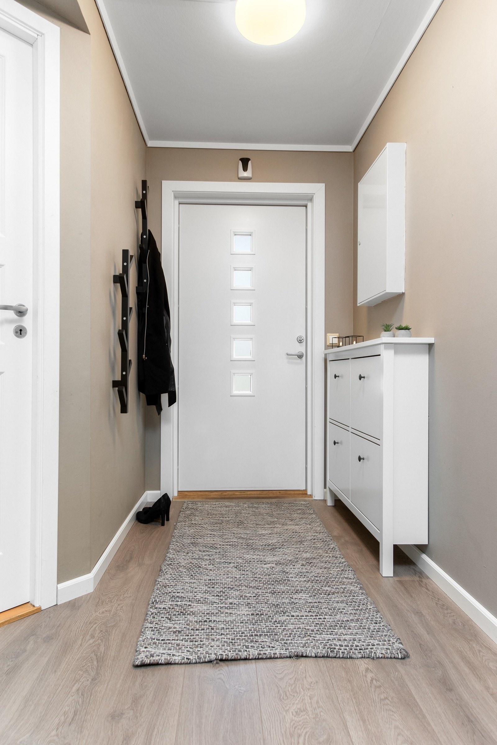 Det er knagger langs den ene veggen og skoskap på den andre. Galleribilde