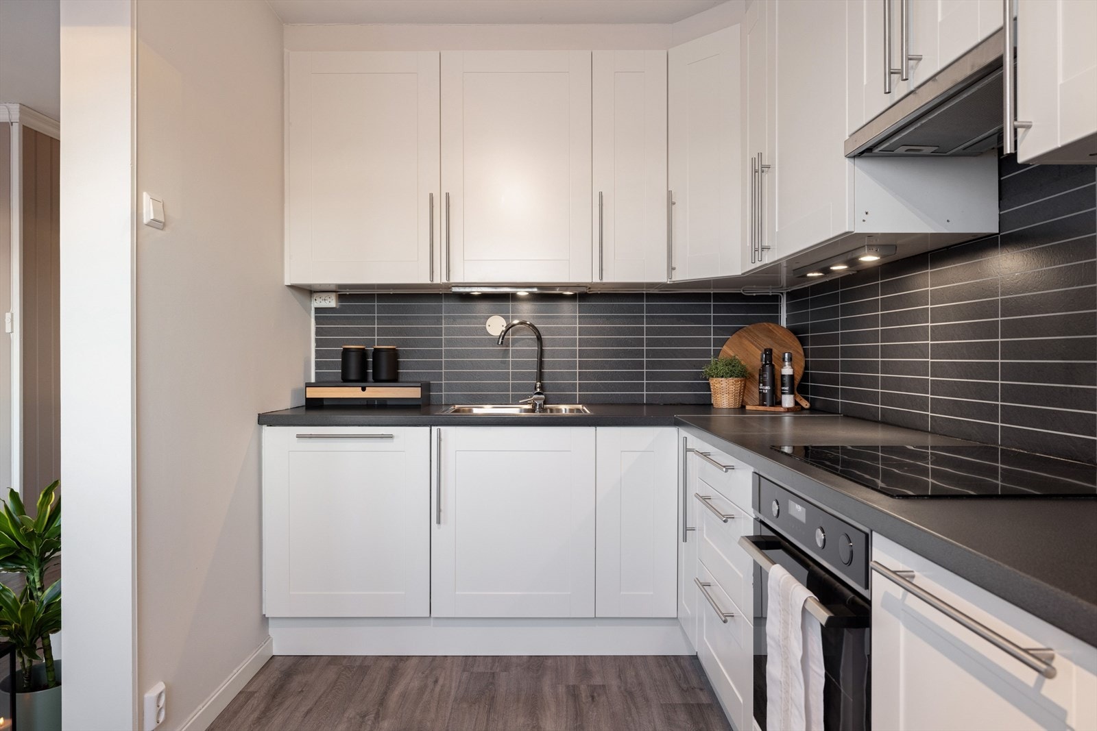 Innredningen har lyse profilerte fronter og laminert benkeplate med nedfelt oppvaskmaskin. Praktisk med plater i benkeryggen og belysning under de takhøye overskapene. Galleribilde