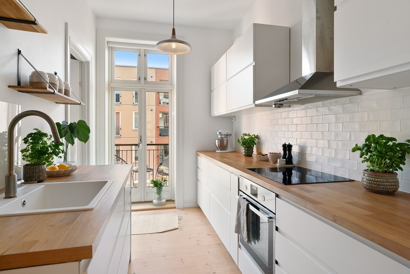 Heltre benkeplate, lekre fliser mellom over- og underskap, integrerte hvitevarer og utgang til balkong Galleribilde