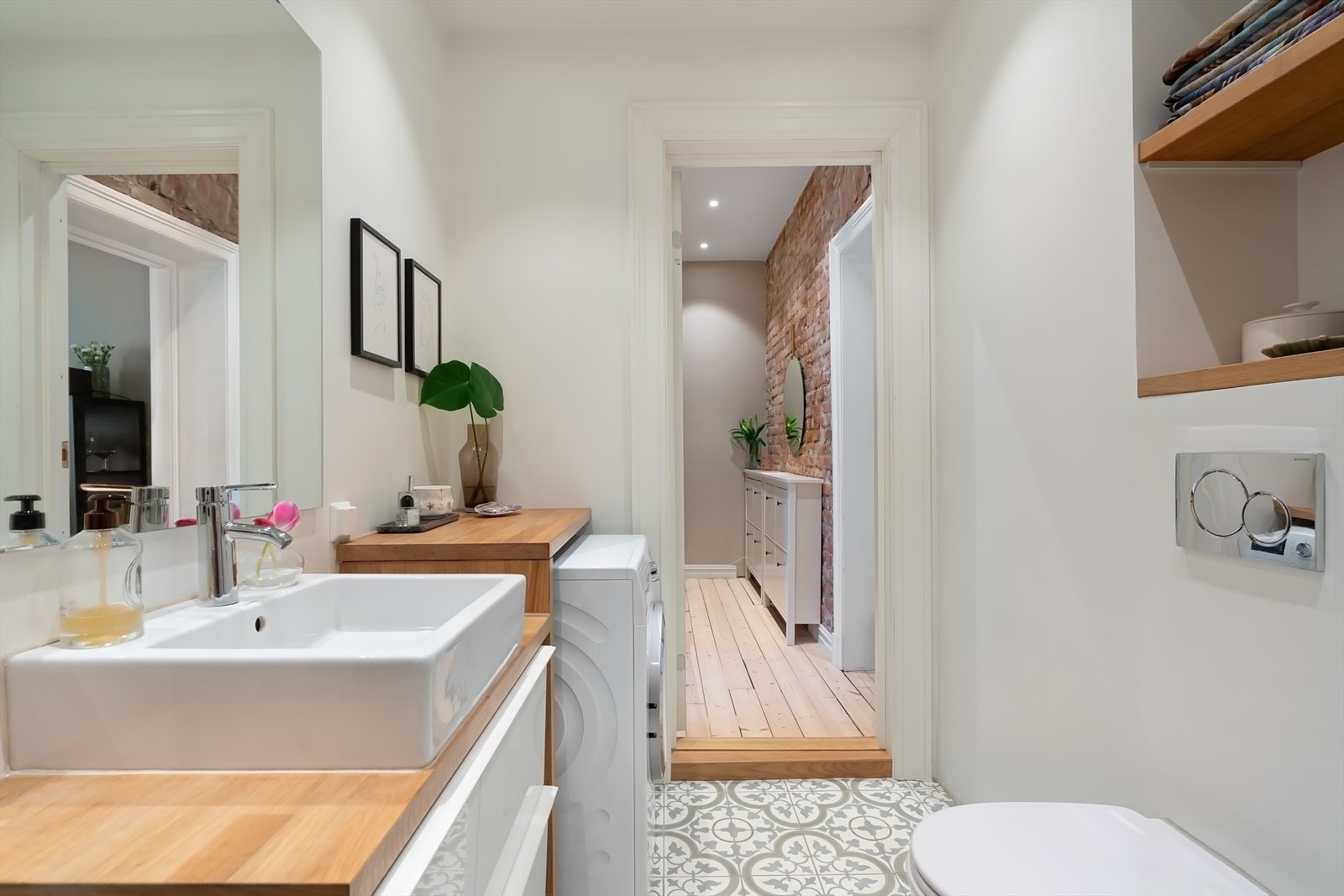 Videre har badet opplegg for vaskemaskin, vask over skuffeløsning og praktiske hyller for oppbevaring Galleribilde