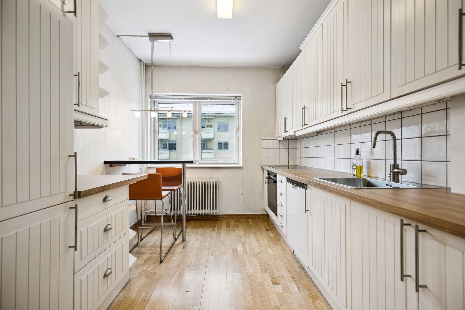 Kjøkkenet er i eget rom med integrerte hvitevarer og koselig spisenisje under vindu Galleribilde