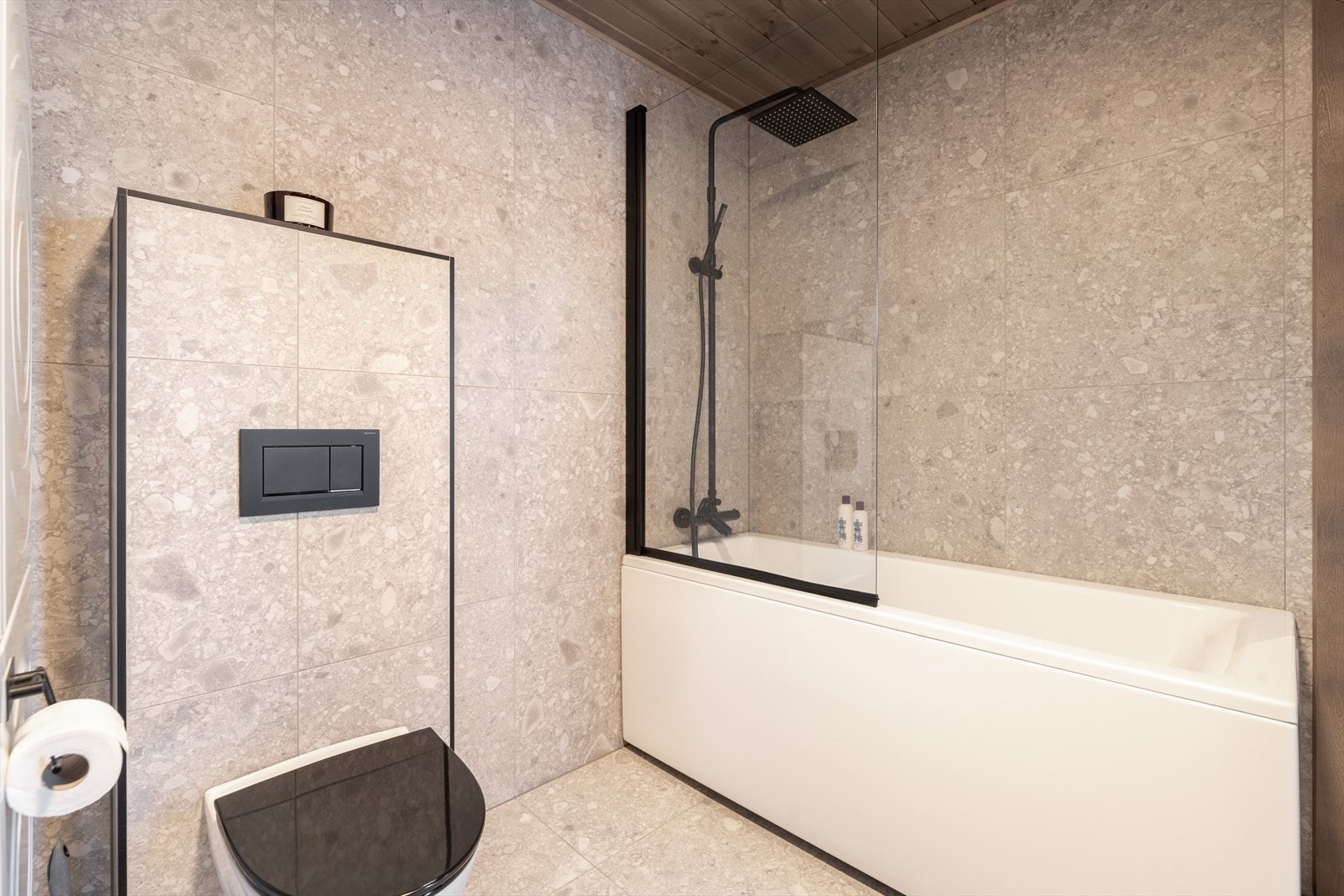 Badet er innredet med vegghengt toalett, badekar med dusj og servantinnredning med underskuffer og speil med lys. Galleribilde