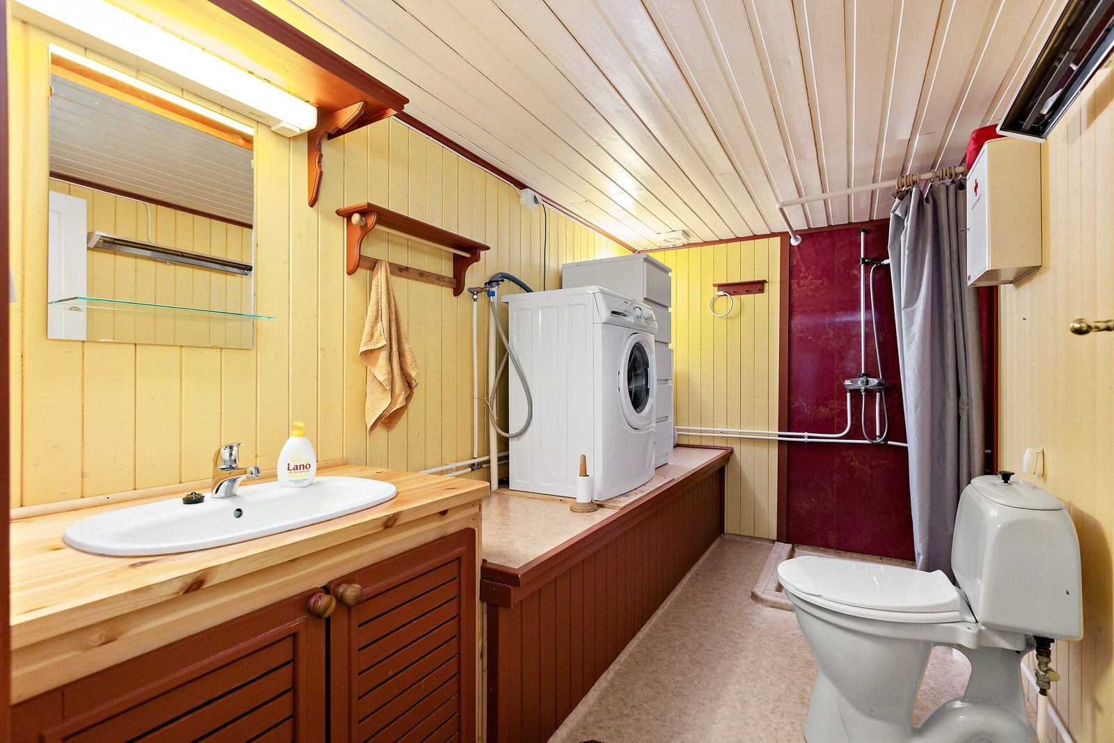 Bad med dusj, toalett, vaskeservant og opplegg for vaskemaskin Galleribilde