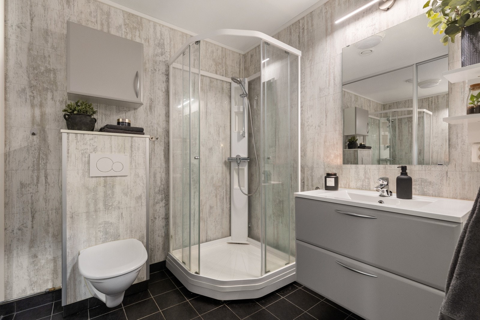 Flott baderom bestående av servant med underskap, vegghengt toalett og dusjkabinett Galleribilde