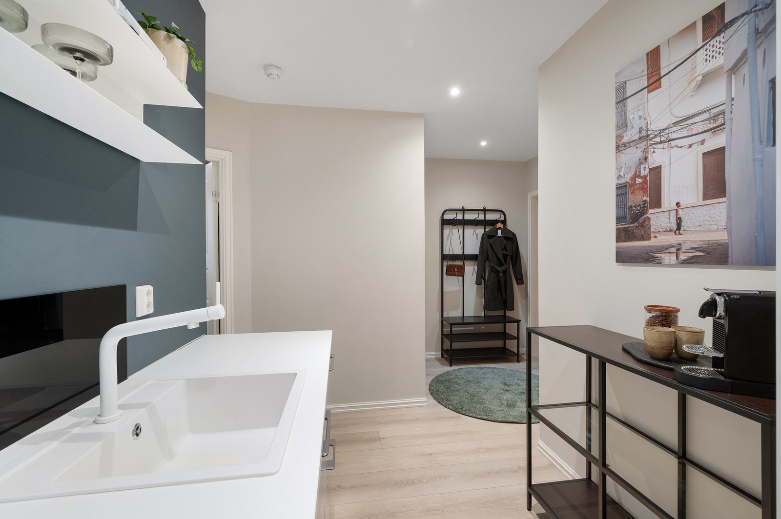 Kjøkkenet preges av hvite detaljer, som blandebatteri, vask, benkeplate og ventilator. Langs kjøkkenbenken er det montert 3 doble stikkontakter. Galleribilde