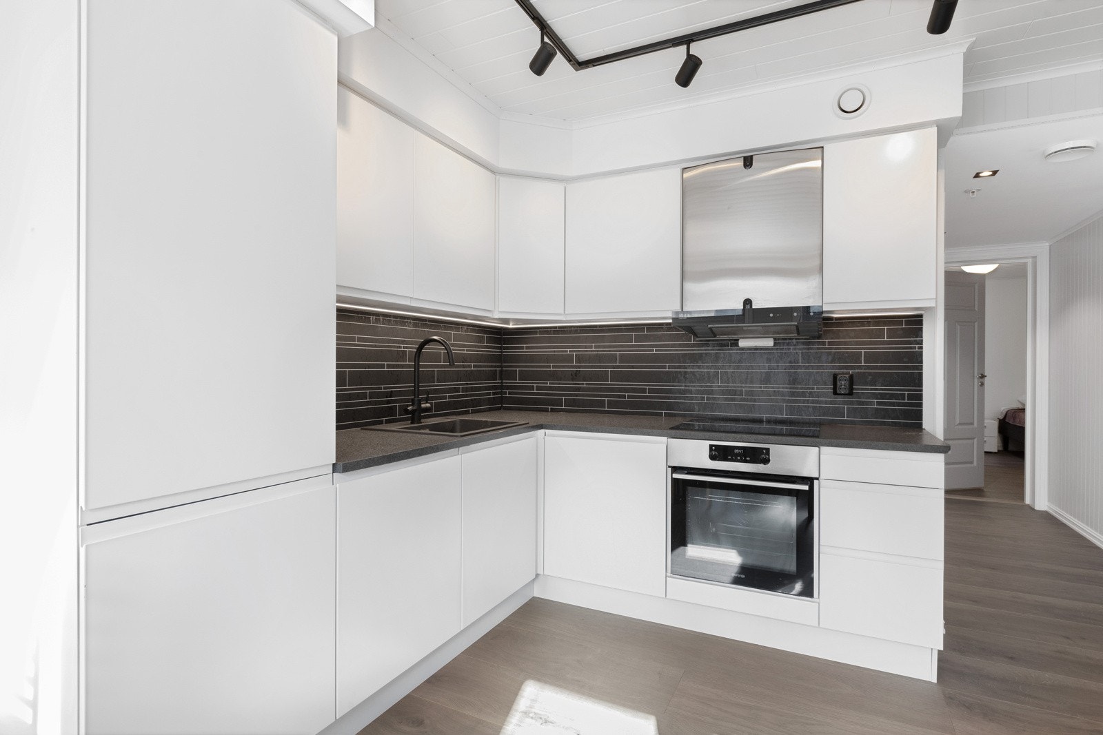 Kjøkken med integrert kjøleskap, oppvaskmaskin, stekeovn og induksjon steketopp. Galleribilde