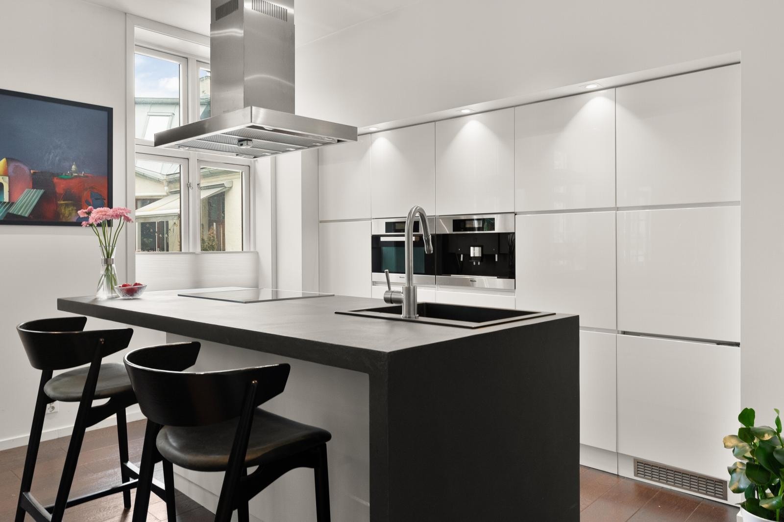 Moderne og velutstyrt kjøkkeninnredning med hvite høyglansfronter og stor kjøkkenøy med spiseplass til flere. Galleribilde