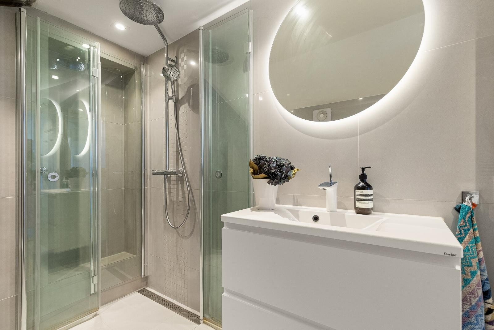 Dusjhjørne med foldbare glassdører. Det er etablert en løsning der rømningsveien er gjenåpnet i egen nisje med glassdør foran rømningsdøren. Badet og løsningen er godkjent av plan og bygg. Galleribilde