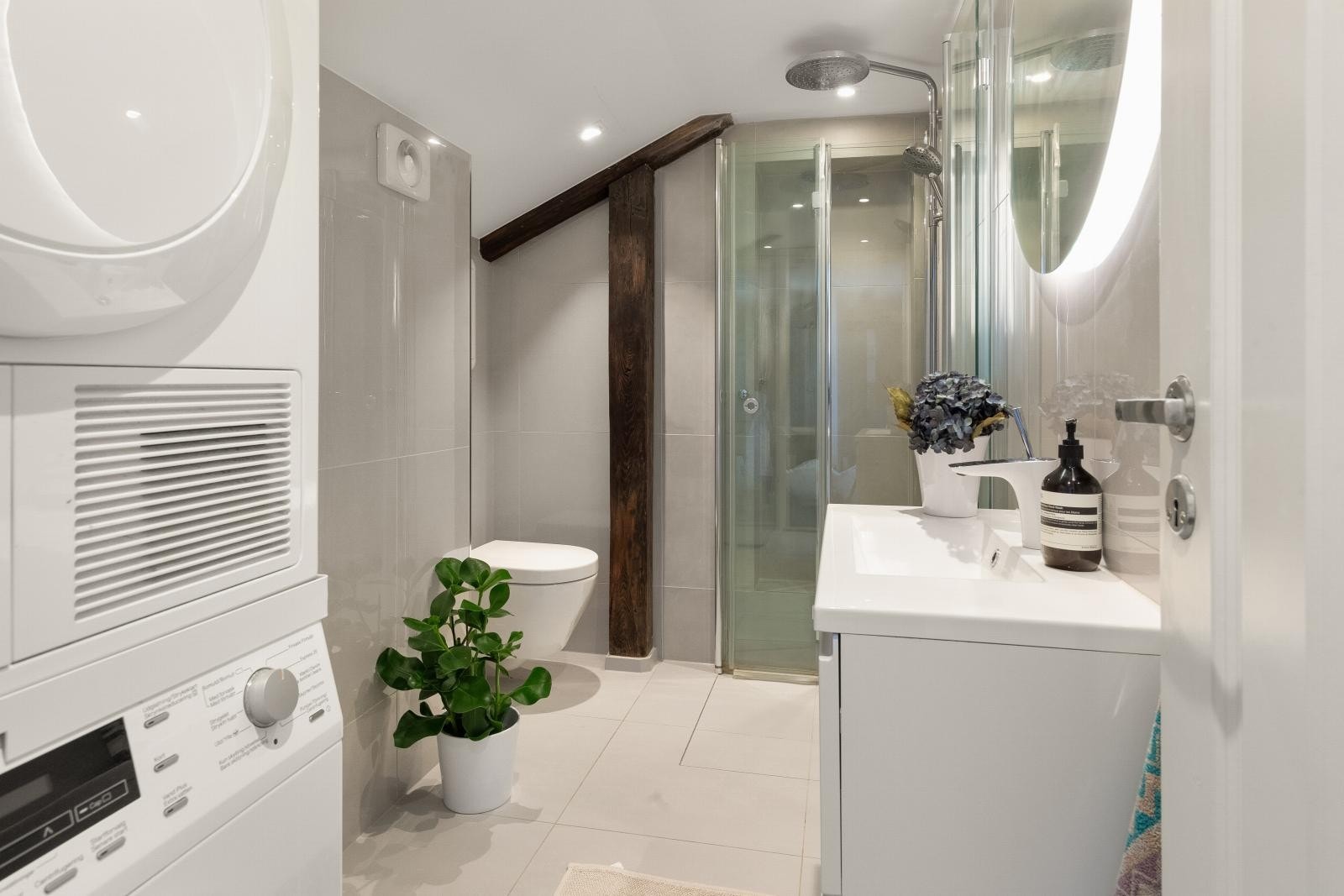 Lekkert, flislagt bad med varmekabler, vegghengt toalett, dusjhjørne med foldbare glassdører og servant med servantskap. Galleribilde