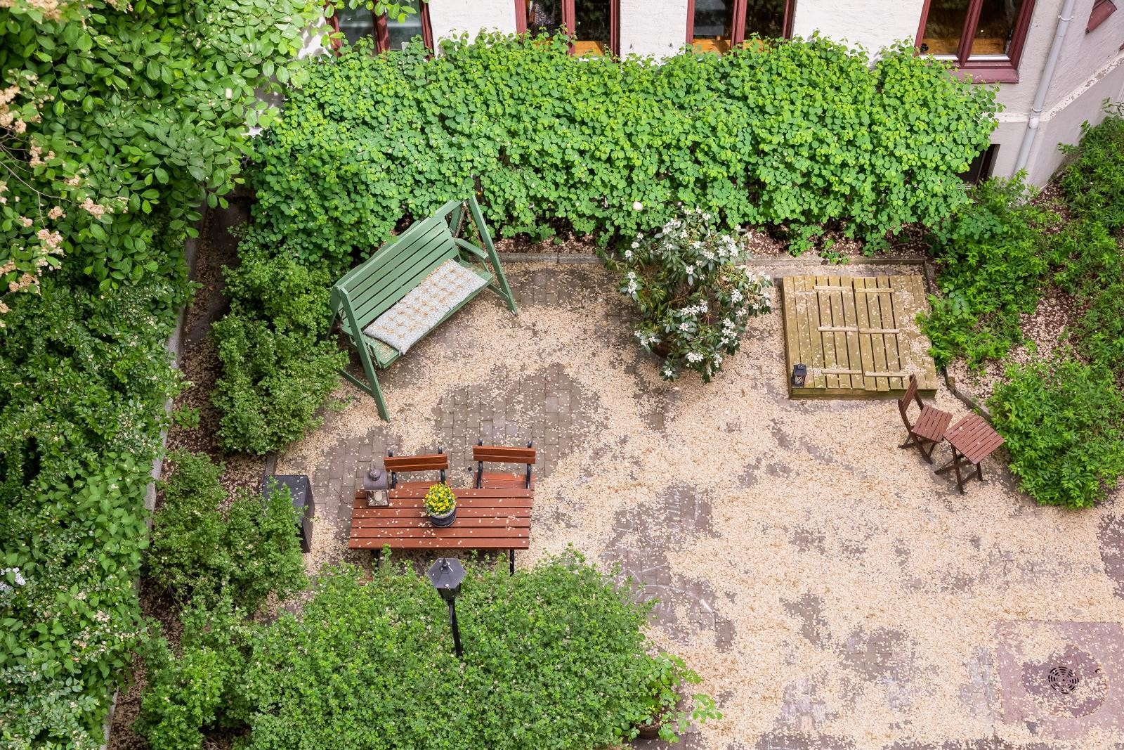 Asfaltert og steinbelagt bakgård med sittegruppe, sykkelparkering og noe beplantninger. Galleribilde