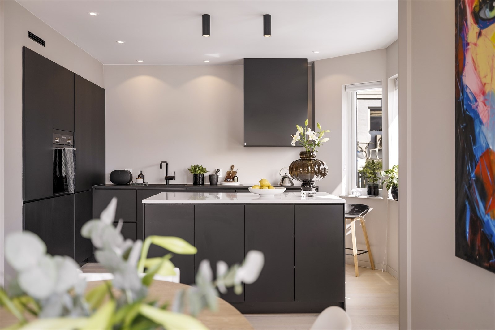 Lekkert og moderne kjøkken fra 2020 utført med slette sorte fronter og benkeplate av laminat (kompositt på kjøkkenøy). Galleribilde