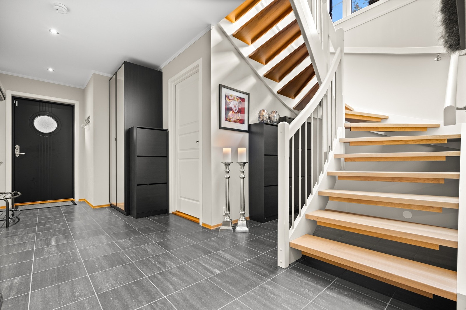 God trapp mellom etasjene med trinn i massiv nyslipt eik og hvitmalt rekkverk med stålspiler. Galleribilde