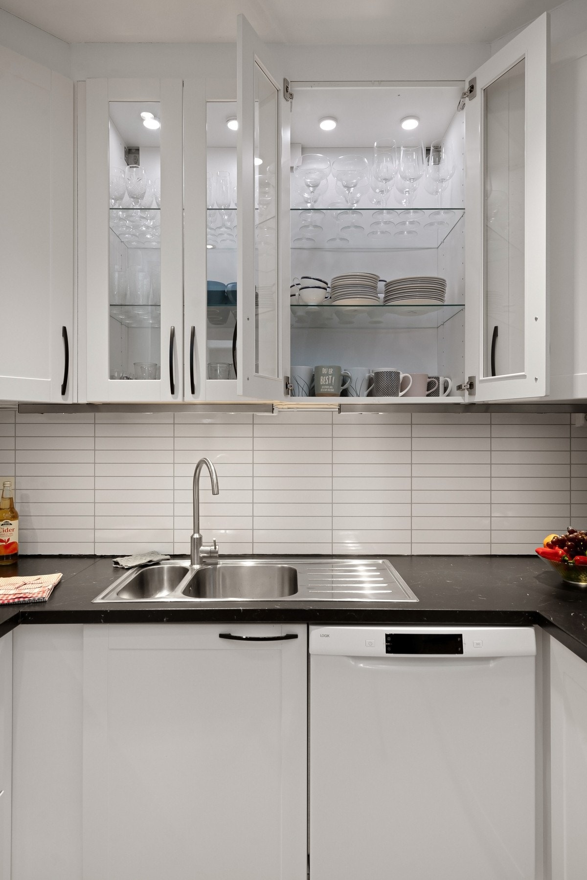 Kjøkkenet har profilerte og vitrine fronter, og benkeplate av laminat. Mellom over- og underskap er det plater. Galleribilde