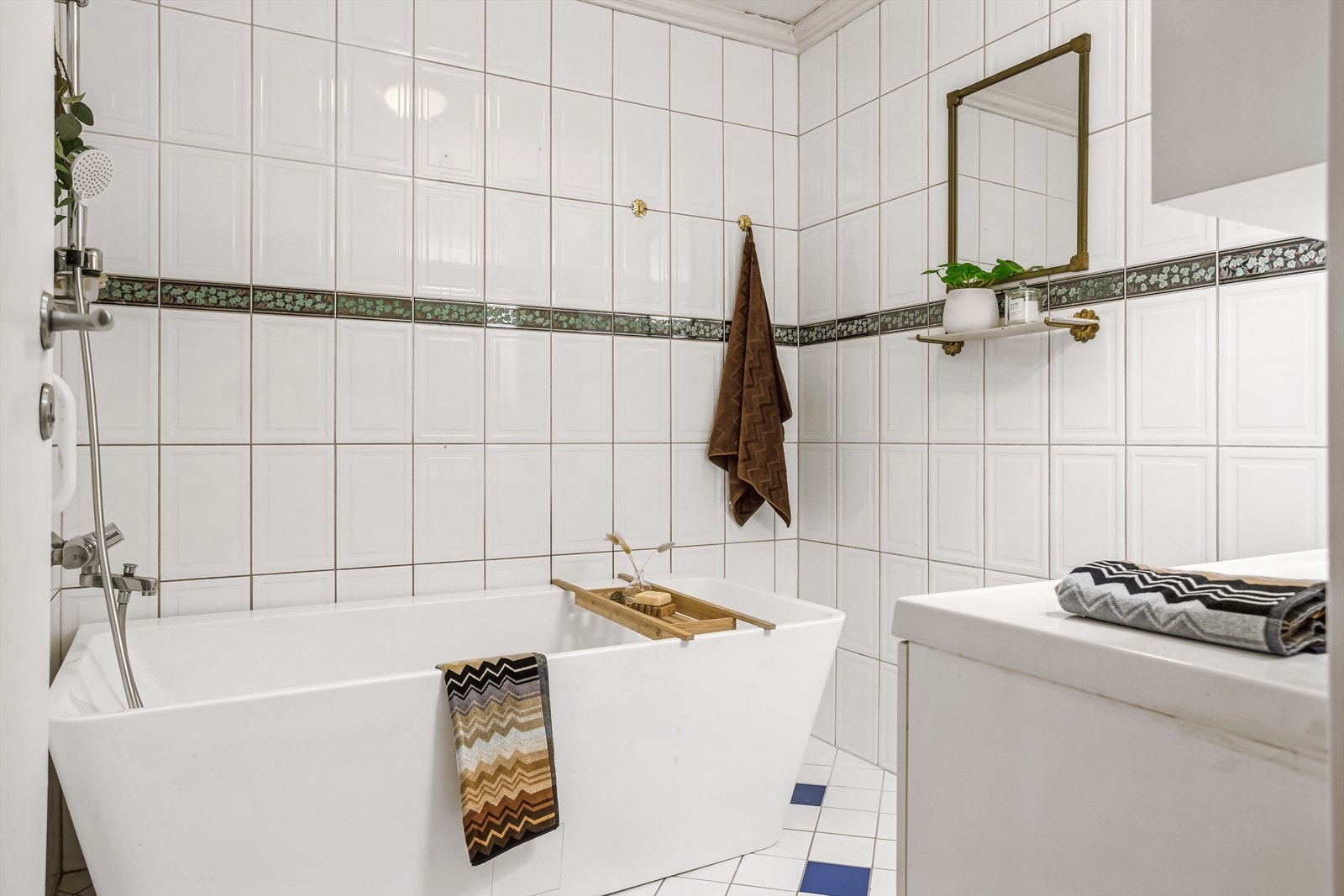 Badet har originale, helflisede overflater og er utstyrt med servant med skapinnredning, samt badekar Galleribilde
