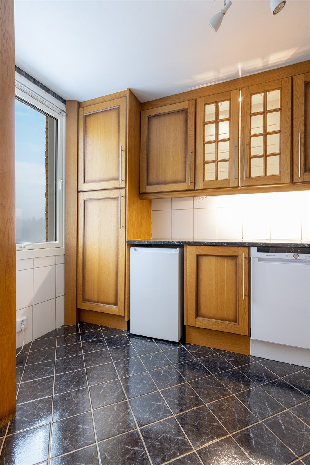 Kjøkkenet har avsatt plass til frittstående hvitevarer som oppvaskmaskin, komfyr og kjøl/fryseskap, og over kokesonen er det ventilator som trolig har utlufting til ventilasjonsaggregat. Galleribilde