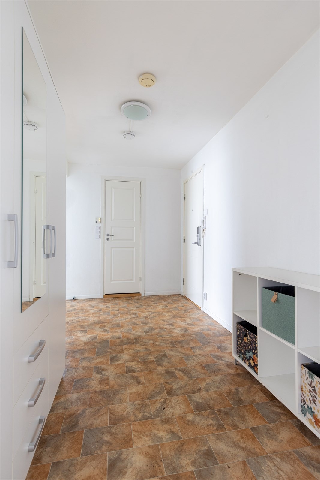 Den romslige entrèen har garderobeskap, og det er også plass til annen mindre møblering. Overflater er belegg på gulv og malte vegger. Galleribilde