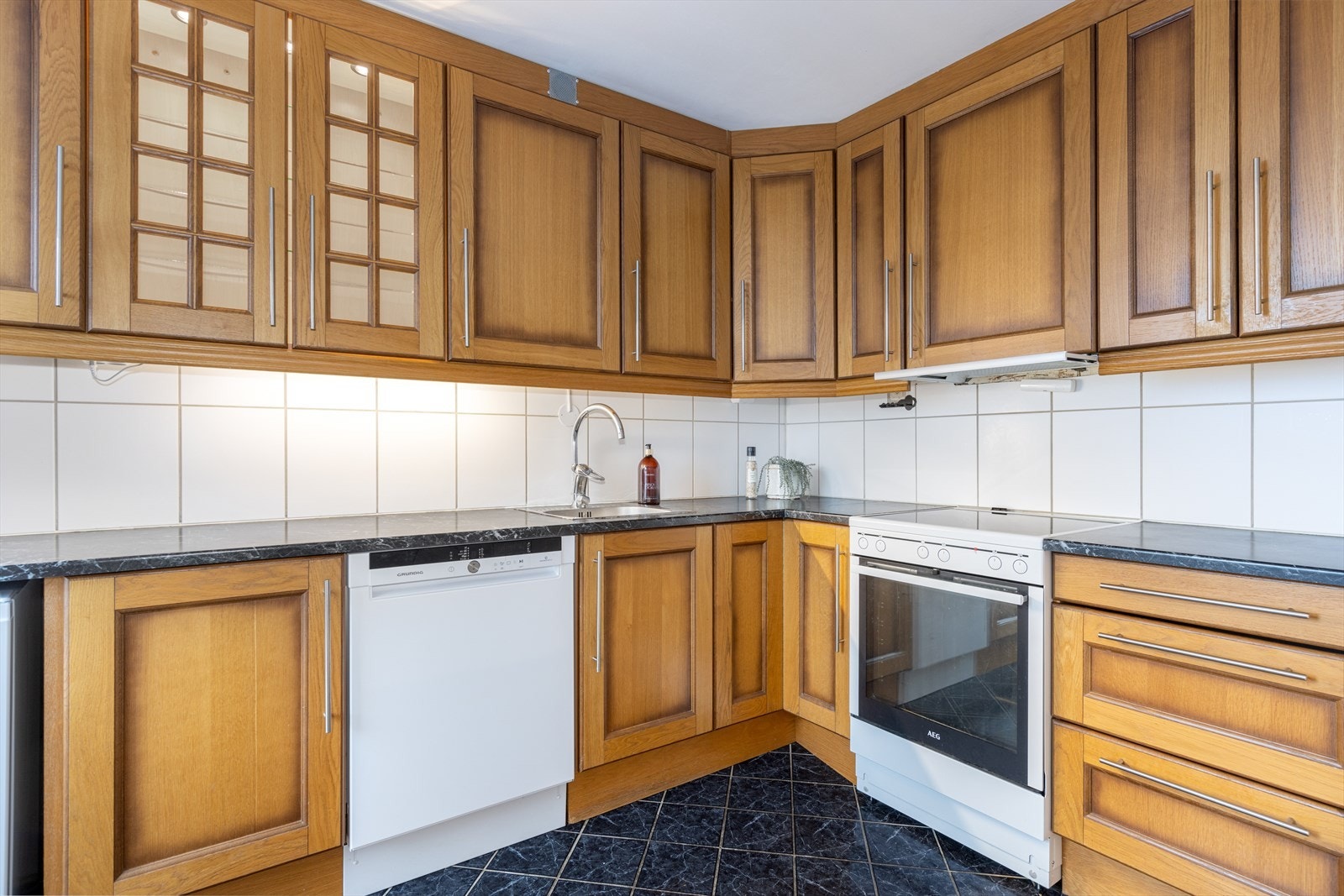 På kjøkkenet er det godt med oppbevaringsplass i innredning med skuffer, takhøye overskap og innslag med glass-skap. Innredningen er i heltre eik, med laminert benkeplate. Galleribilde