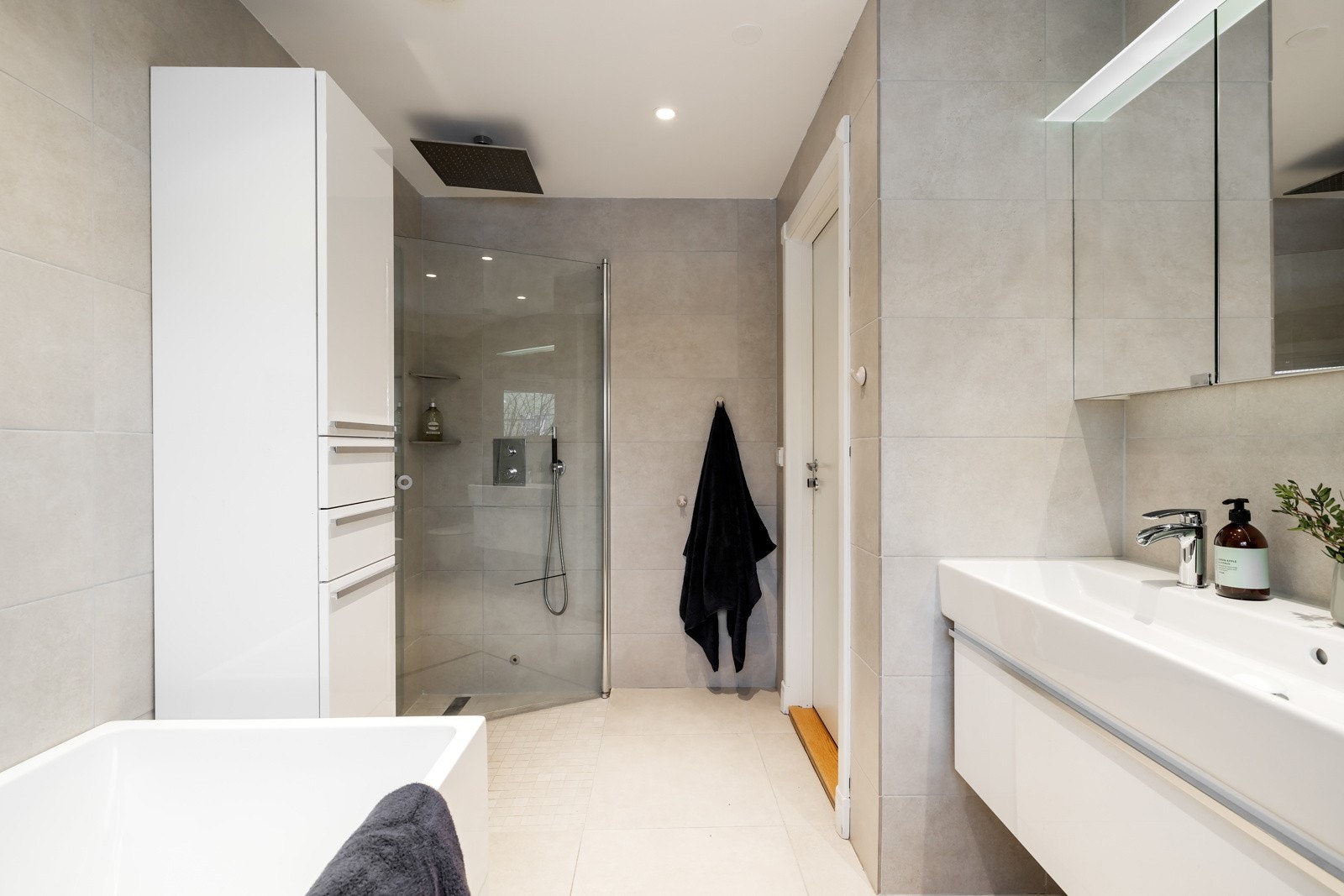 Det er rikelig med oppbevaringsplass i skapet, samt skaperne bak speilet og i skuffen under servanten. Dusjhjørnet har glassdører og en stor regnfallsdusj. Galleribilde