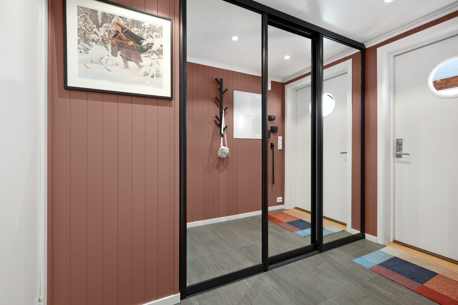 Praktisk gang med skyvedørsgarderobe og gulv med fliser og varme Galleribilde