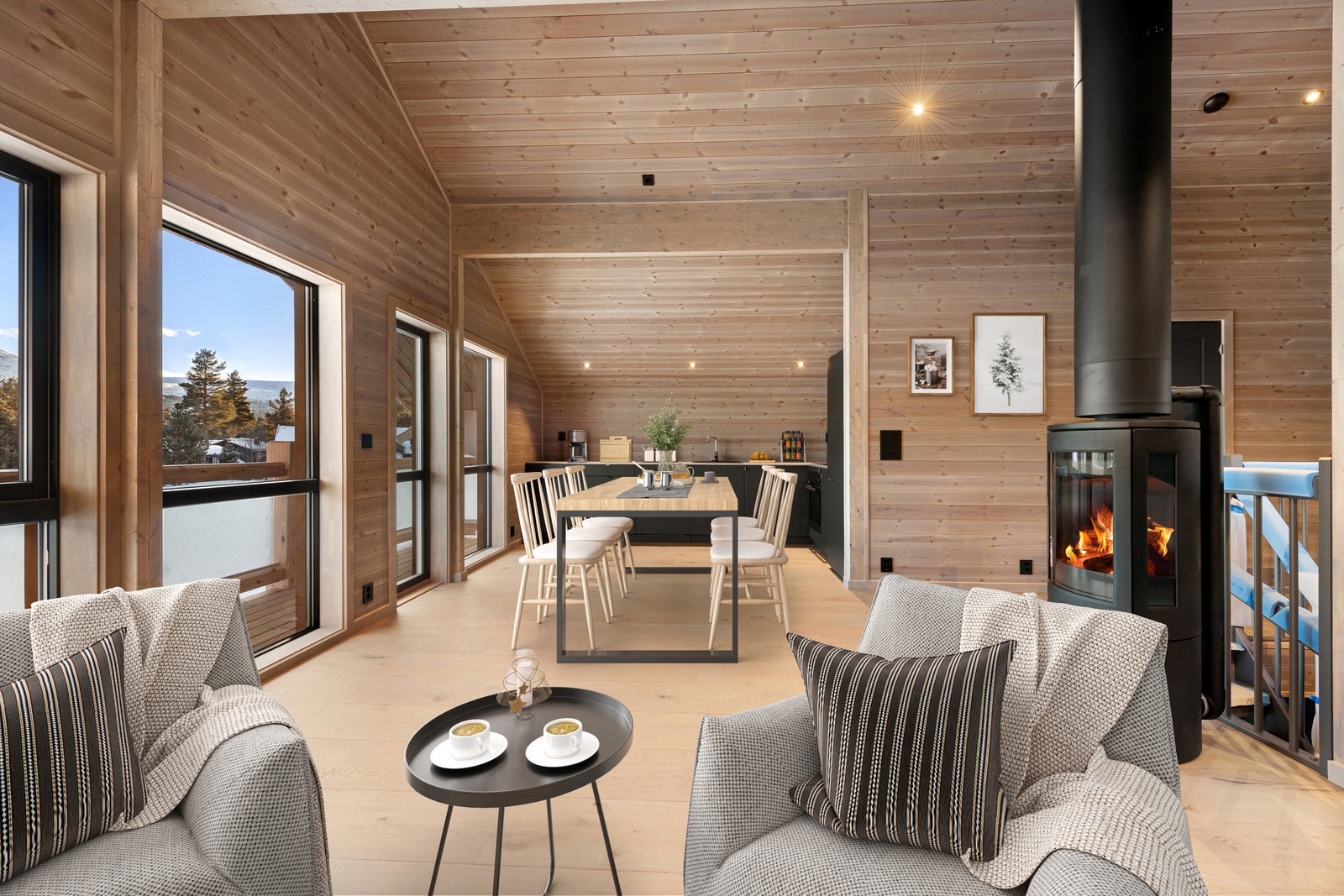 Hytta har en åpen stue- og kjøkkenløsning med ovnen som midtpunkt. Bildet er digitalt møblert. Galleribilde