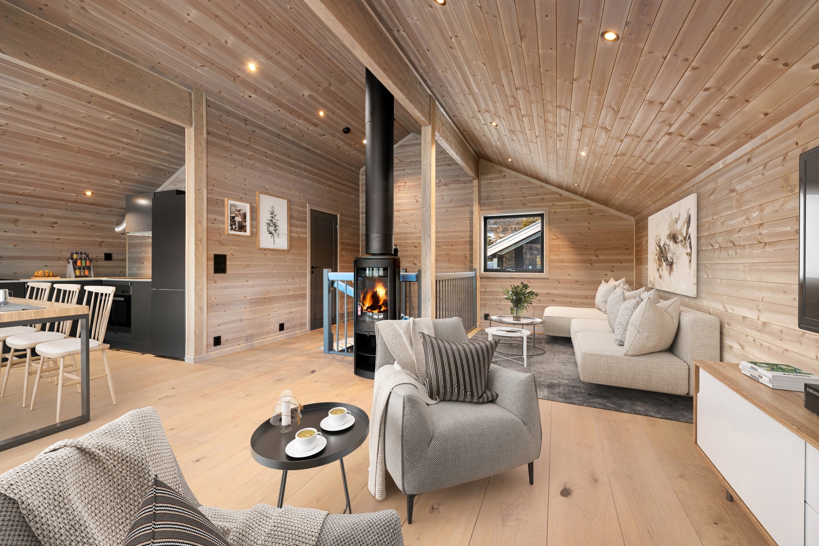 Hytta har en åpen stue- og kjøkkenløsning med ovnen som midtpunkt. Bildet er digitalt møblert. Galleribilde