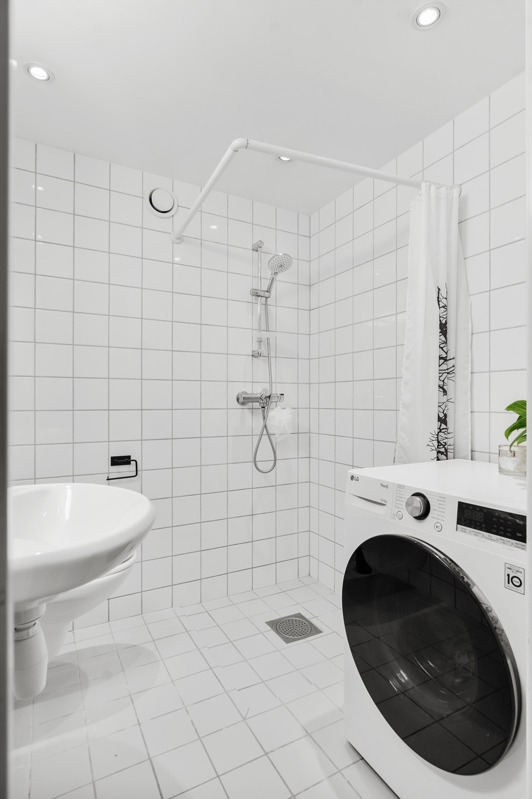 Videre er badet utstyrt med dusjhjørne med forheng med blandebatteri fra Oras, opplegg for vaskemaskin og veggmontert toalett. Galleribilde