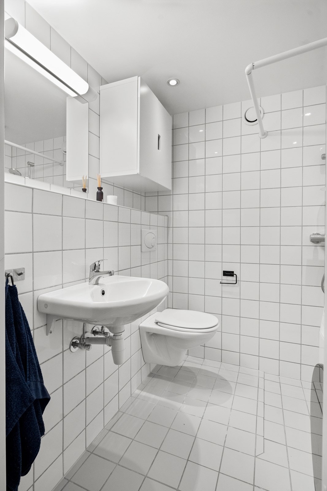 Badet har hvit servant med blandebatteri fra Damixa, vegghengt speil med belysning og et vannfordelerskap. Galleribilde