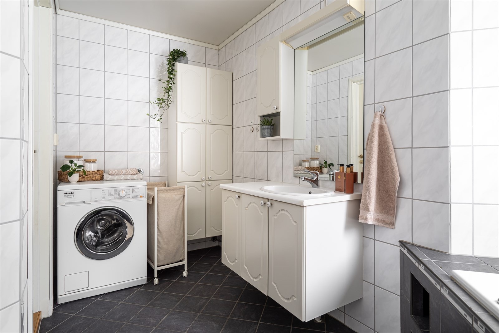 Badet har toalett, varmekabler, servant på underskap og et innfliset badekar med dusjløsning Galleribilde