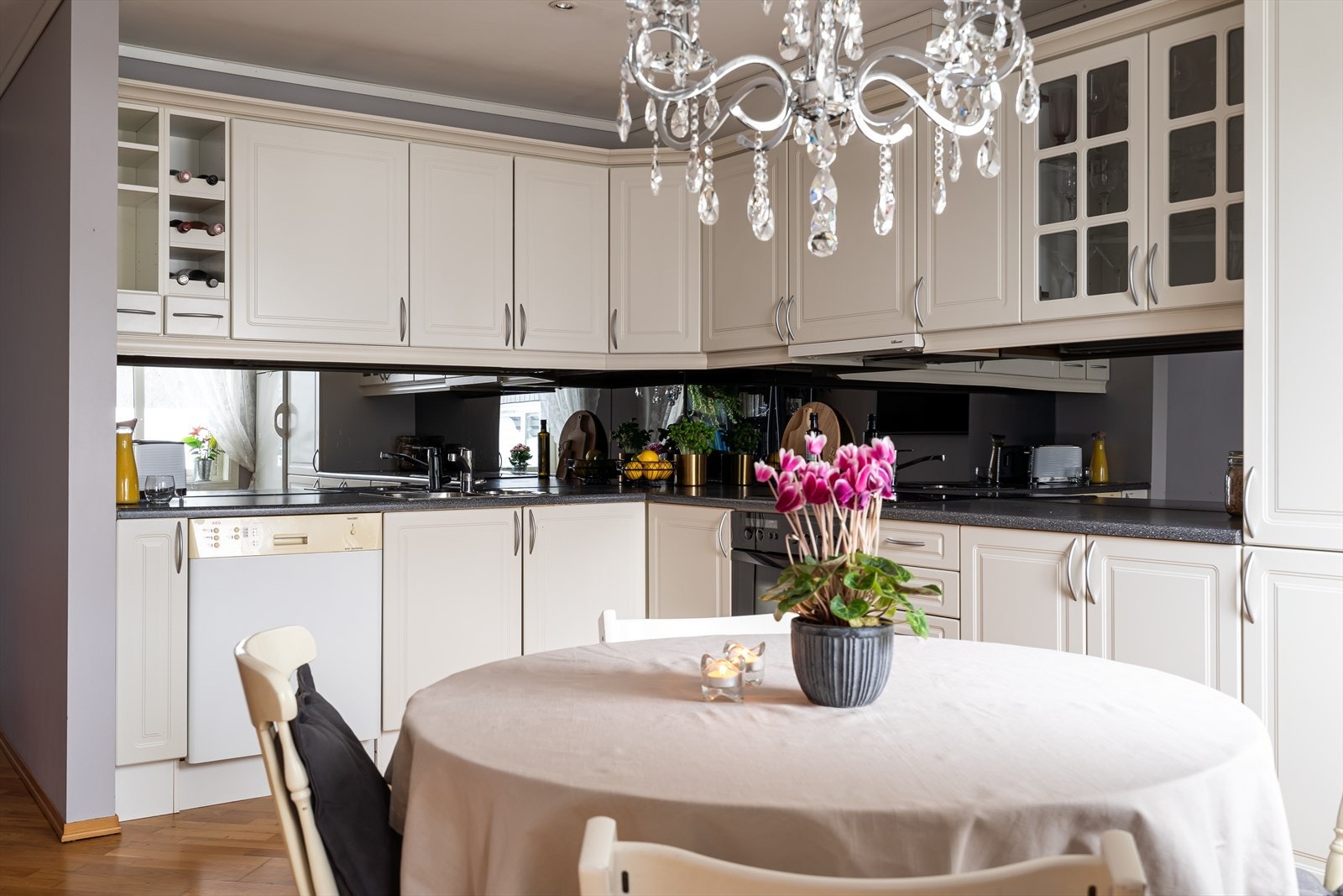 Kjøkkenet er oppført i en funksjonell L-form med god arbeidsflyt og skapplass. Innredningen har vinhylle, vitrineskap, hvite, profilerte fronter og laminert benkeplate med nedfelt oppvaskkum. Galleribilde