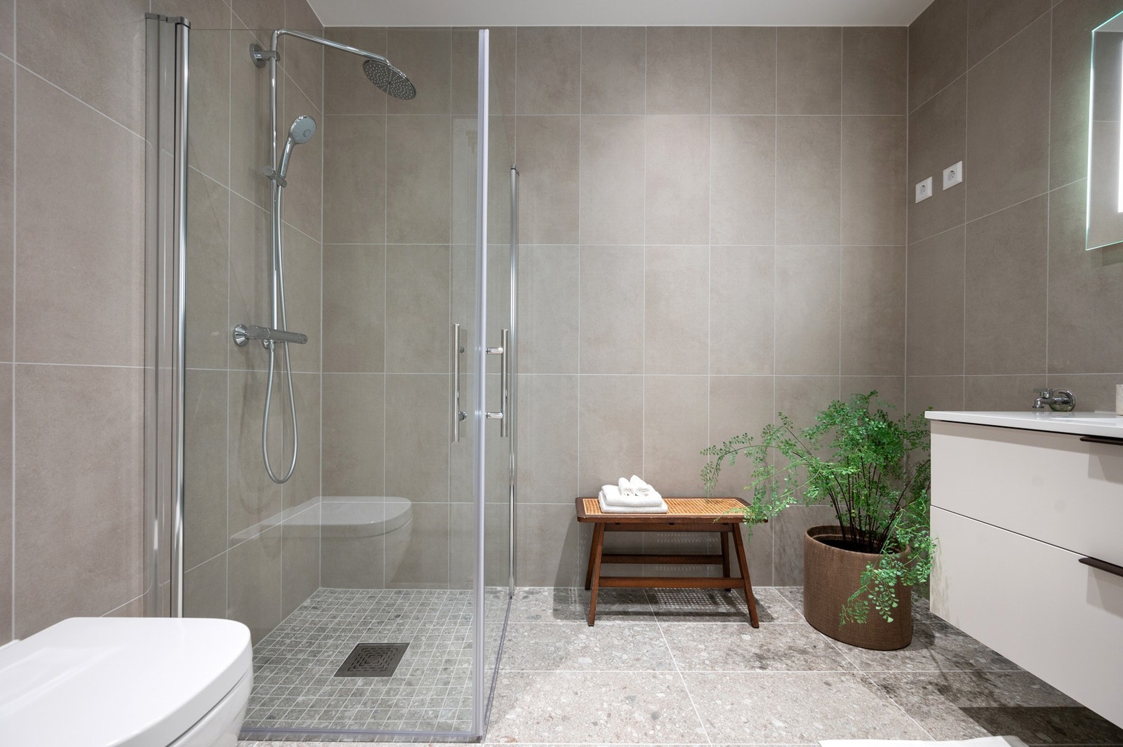 Pent bad innredet med servantinnredning, speil, dusjhjørne med regndusj, toalett og opplegg for vaskemaskin. Galleribilde