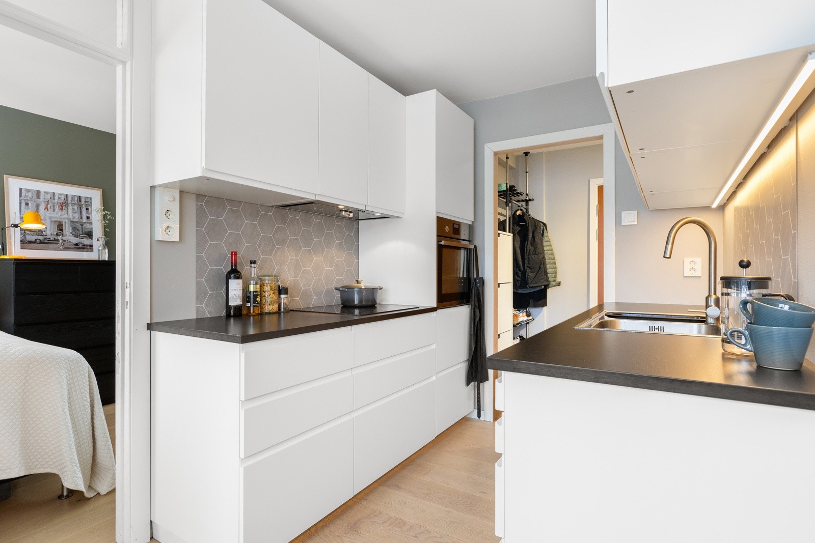 Pent kjøkken fra 2015 med glatte fronter og laminat benkeplate med nedfelt kum i rustfritt stål. Galleribilde