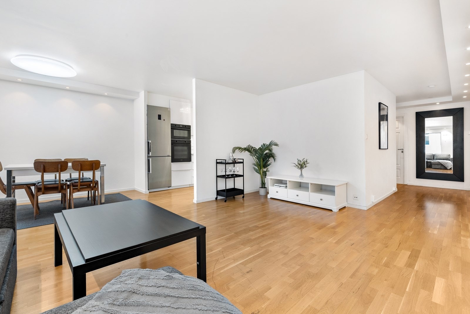 Stort oppholdsrom med kjøkken i åpen løsning, hvor kjøkkenet allikevel er tilbaketrukket og kan deles av til et separat kjøkken. Galleribilde