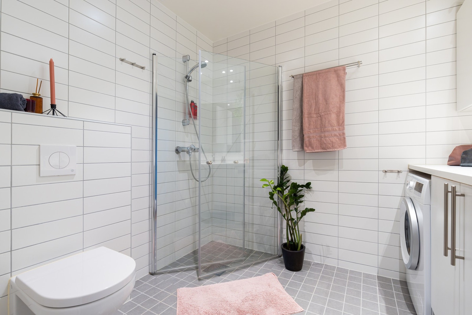 Badet har opplegg for vaskemaskin og plass til tørketrommel i praktisk og plassbesparende nisje. Galleribilde