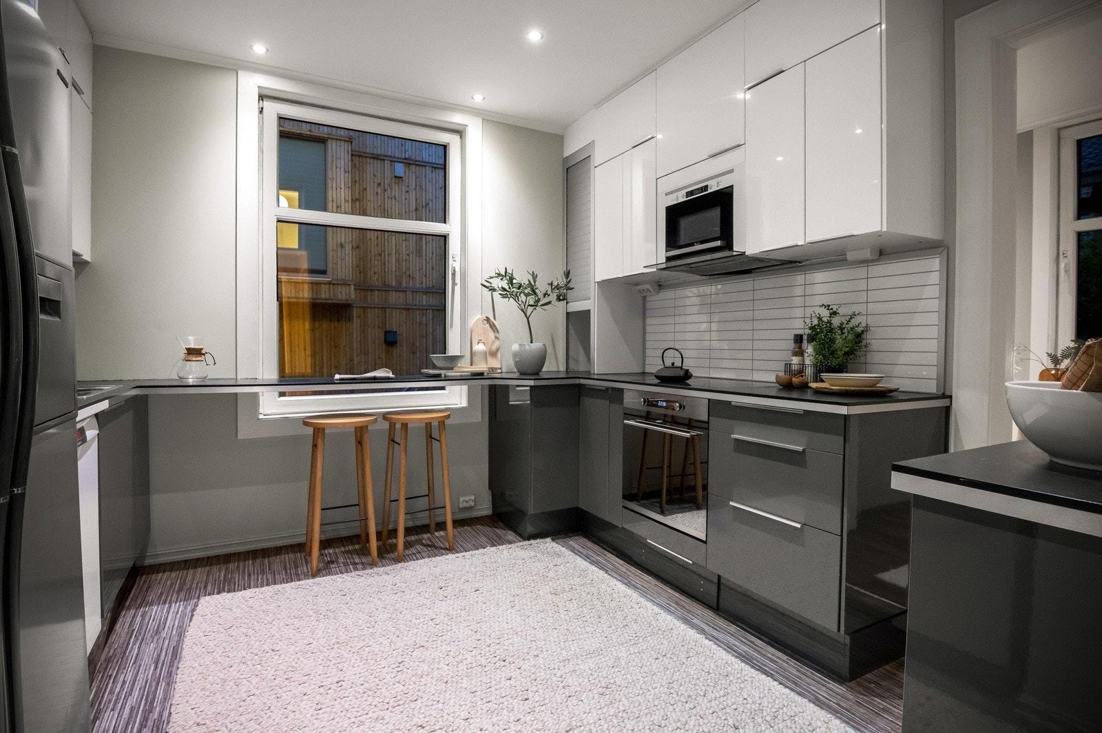 Innredningen har benkeskap med mørkegrå høyglansfronter, takhøye overskap med hvite høyglansfronter og benkeplater i mørk laminat Galleribilde