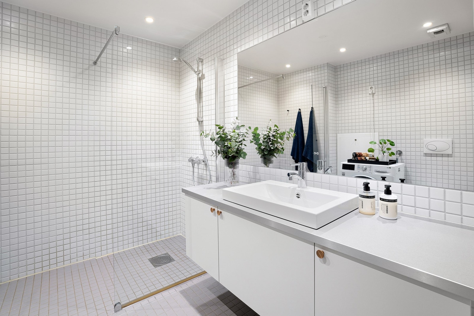 Flislagt romslig baderom med gulvvarme og opplegg for vaskemaskin. Galleribilde