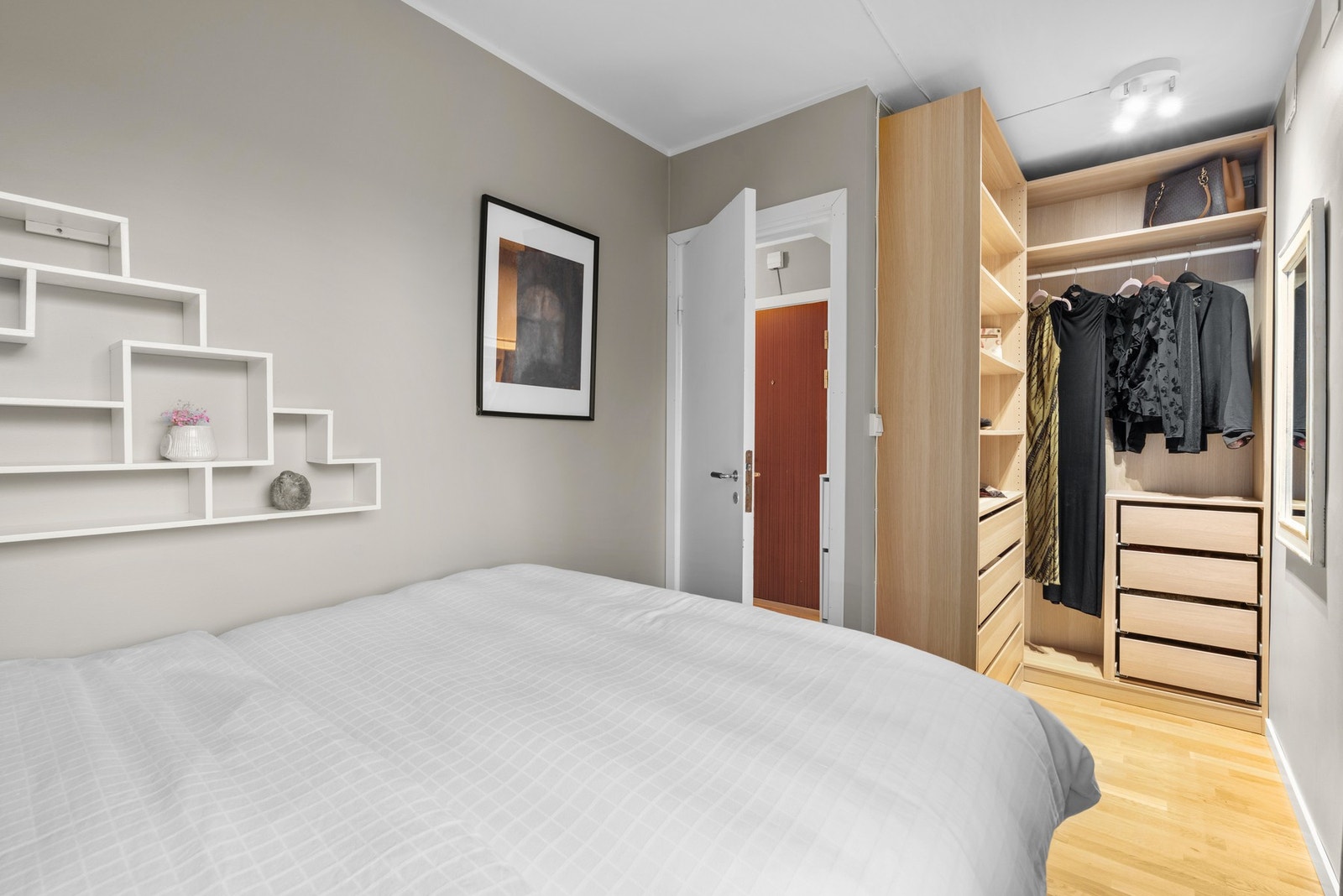 For oppbevaring er det montert en stilig garderobeløsning med hyller, skuffer og stang til oppheng av tøy. Galleribilde