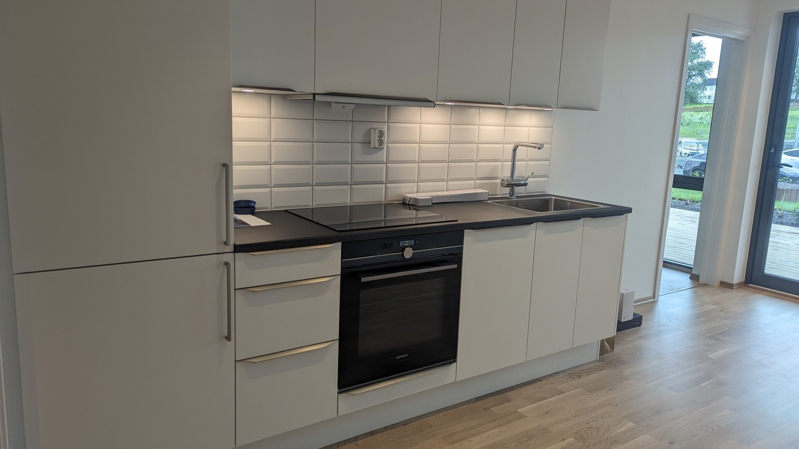 Lyst og pent kjøkken med integrerte hvitevarer Galleribilde