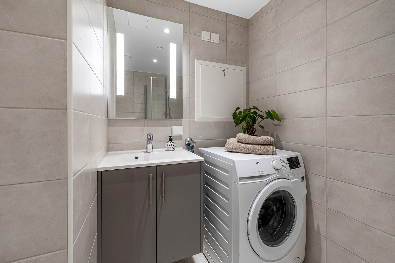 Badet er utstyrt med innredning med glatte fronter og opplegg for vaskemaskin. Galleribilde