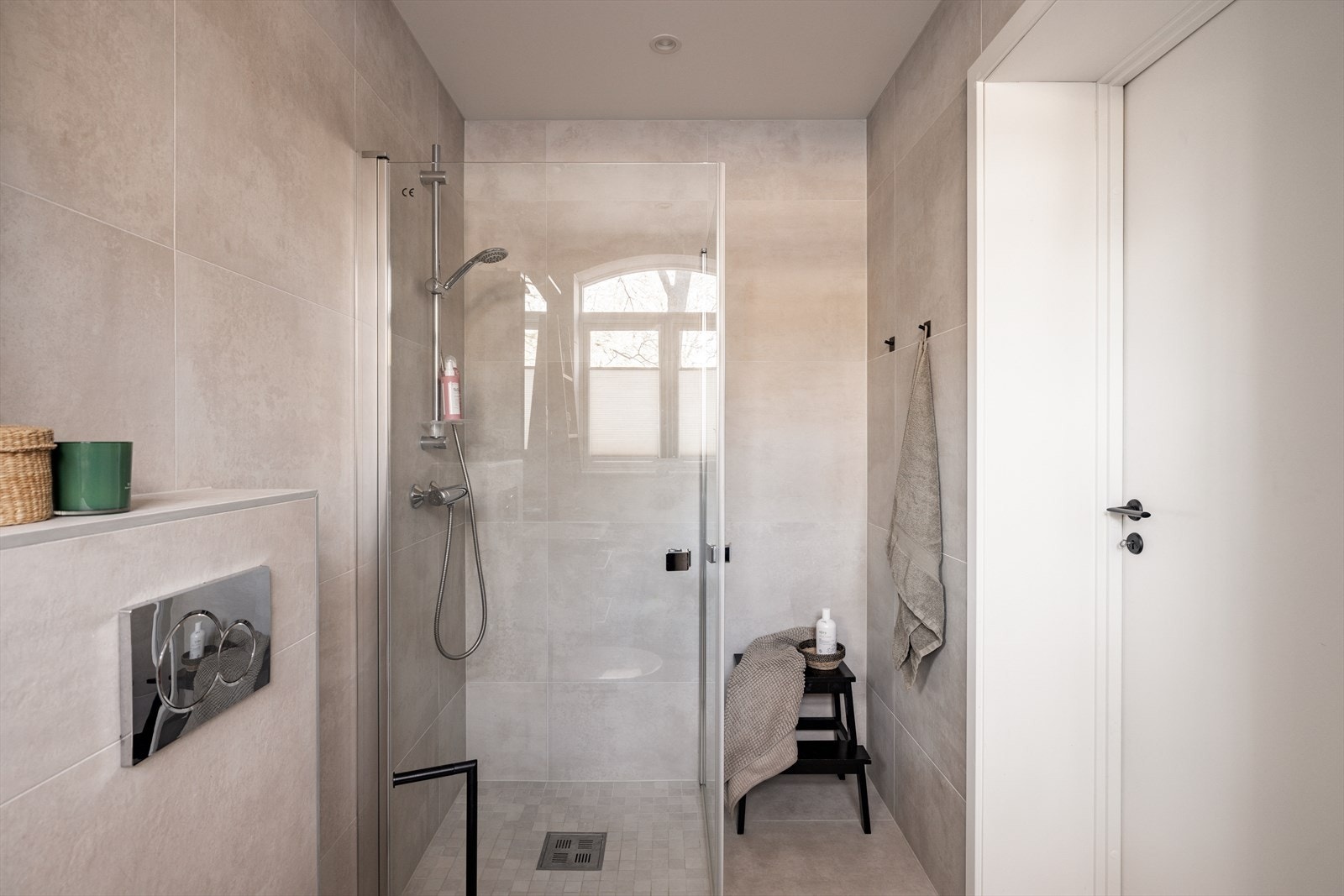 Baderomsinnredningen består av servant med skuffeseksjoner, speil med lys, veggmontert toalett, dushjørne og opplegg for vaskemaskin Galleribilde