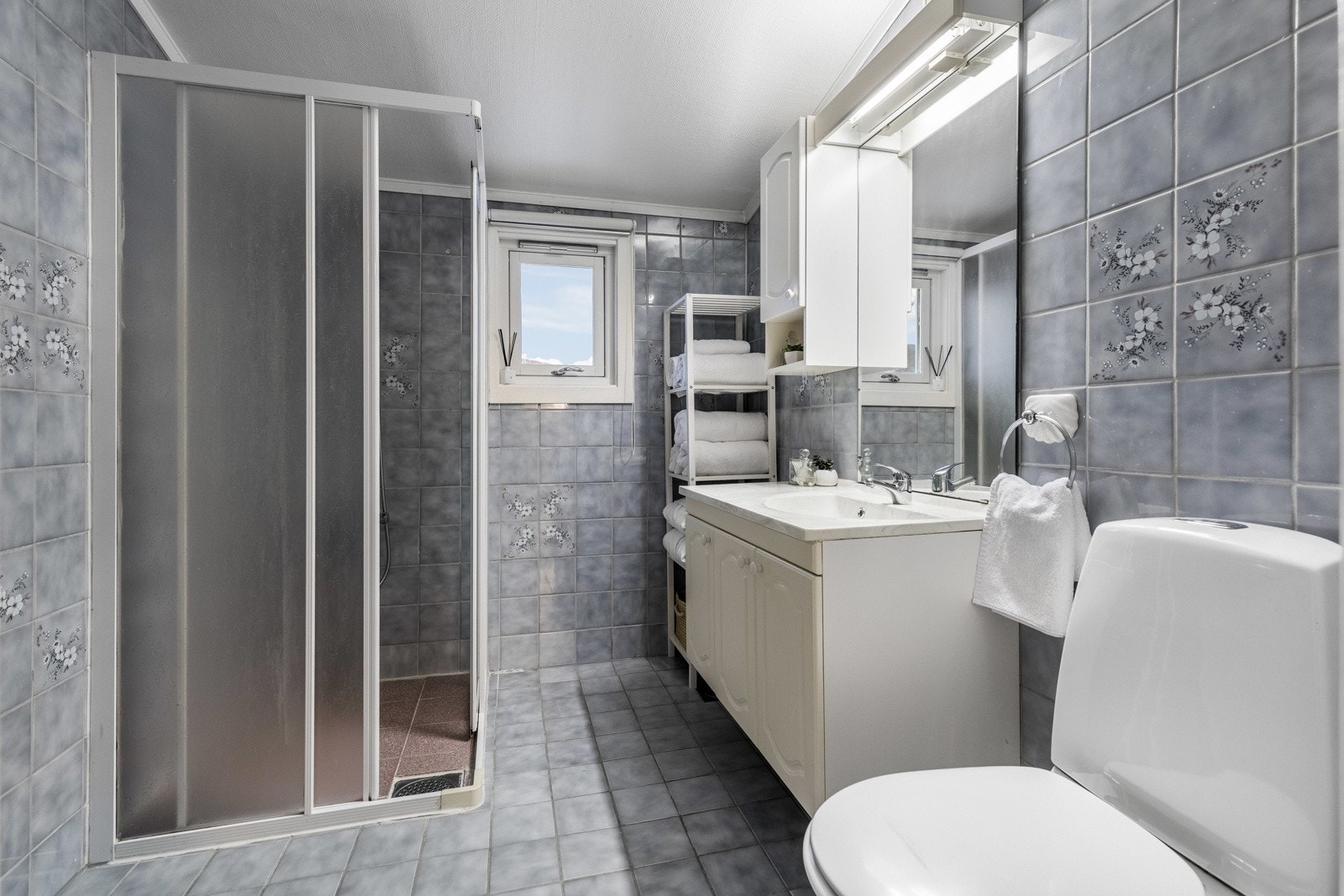 Boligen har et bad i andre etasje og et eget vaskerom i kjelleren. Badet er innredet med grå fliser, og har toalett, gulvvarme og et dusjhjørne med skyvedører. Galleribilde