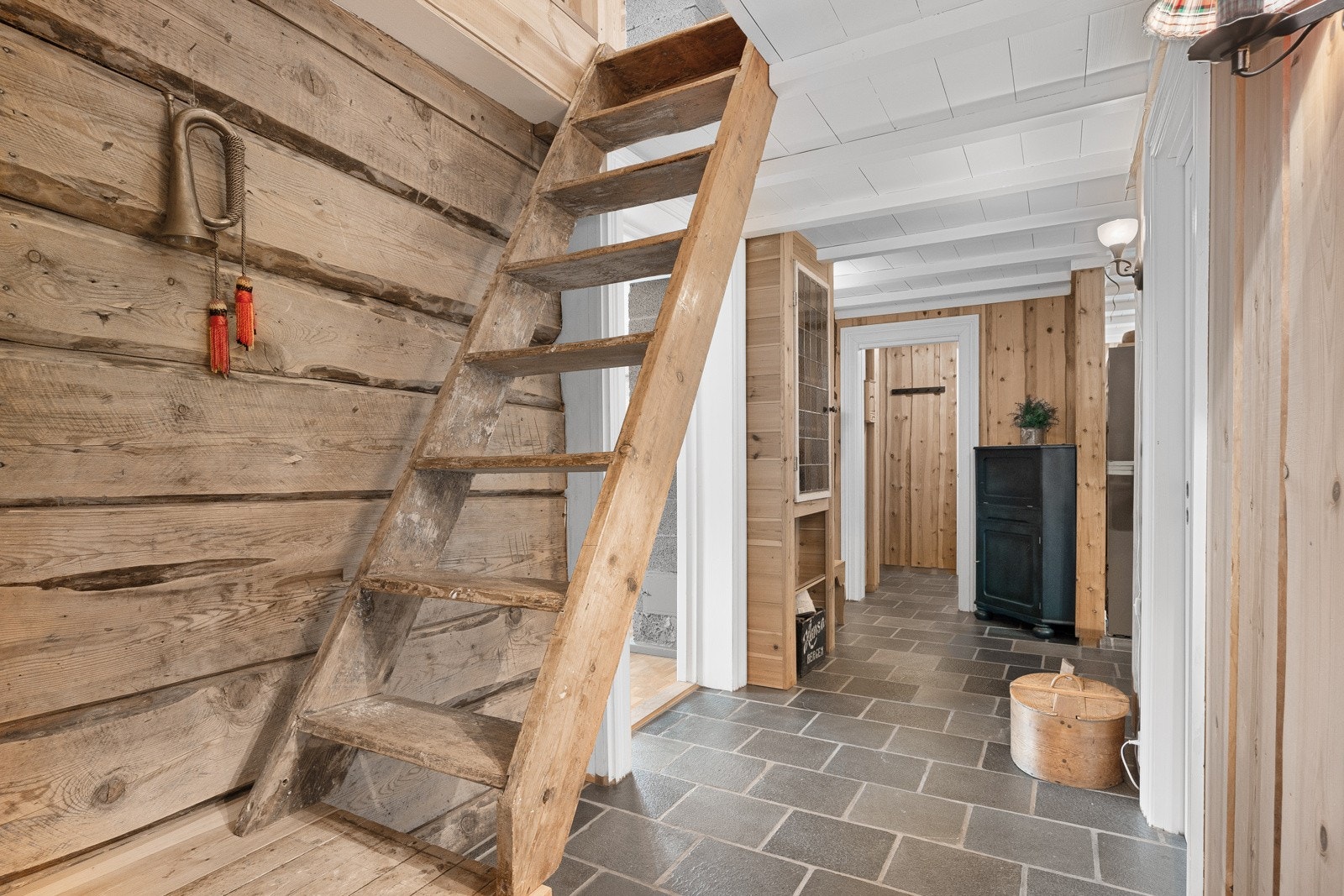 Vindfang og gang har skiferfliser på gulvet med varme, panel på vegger og hvitmalte tak. Galleribilde