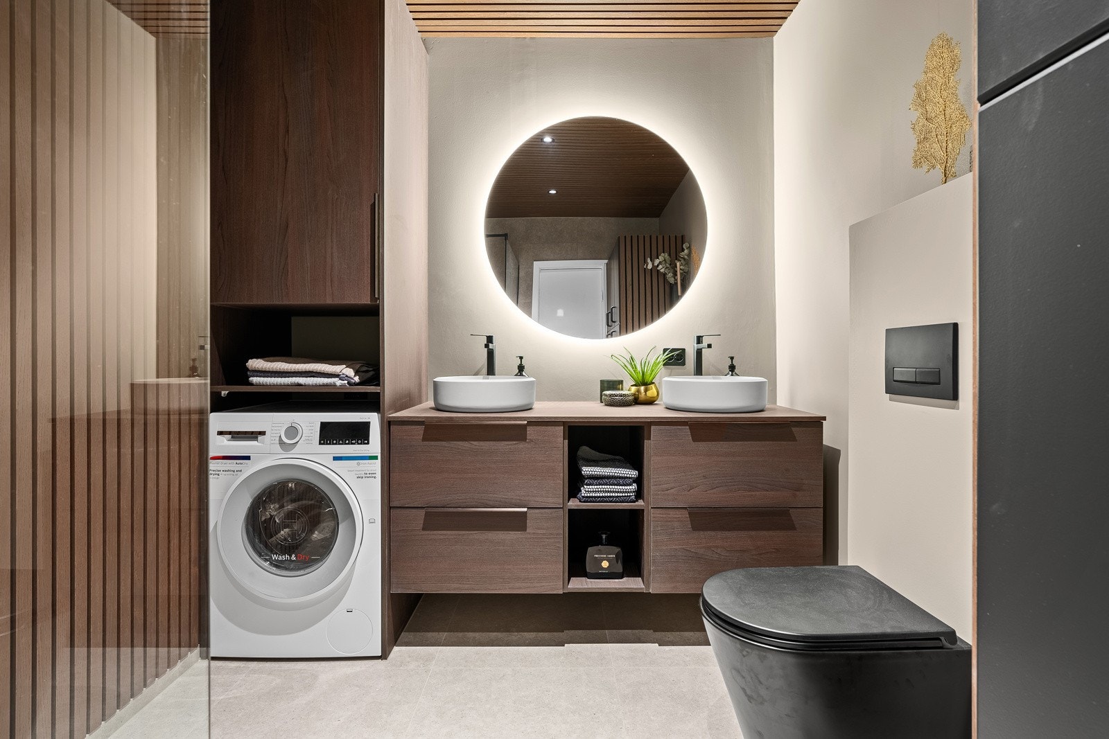 Lekkert flislagt bad med vegghengt toalett, dobbelservant med innredning og opplegg til vaskemaskin Galleribilde