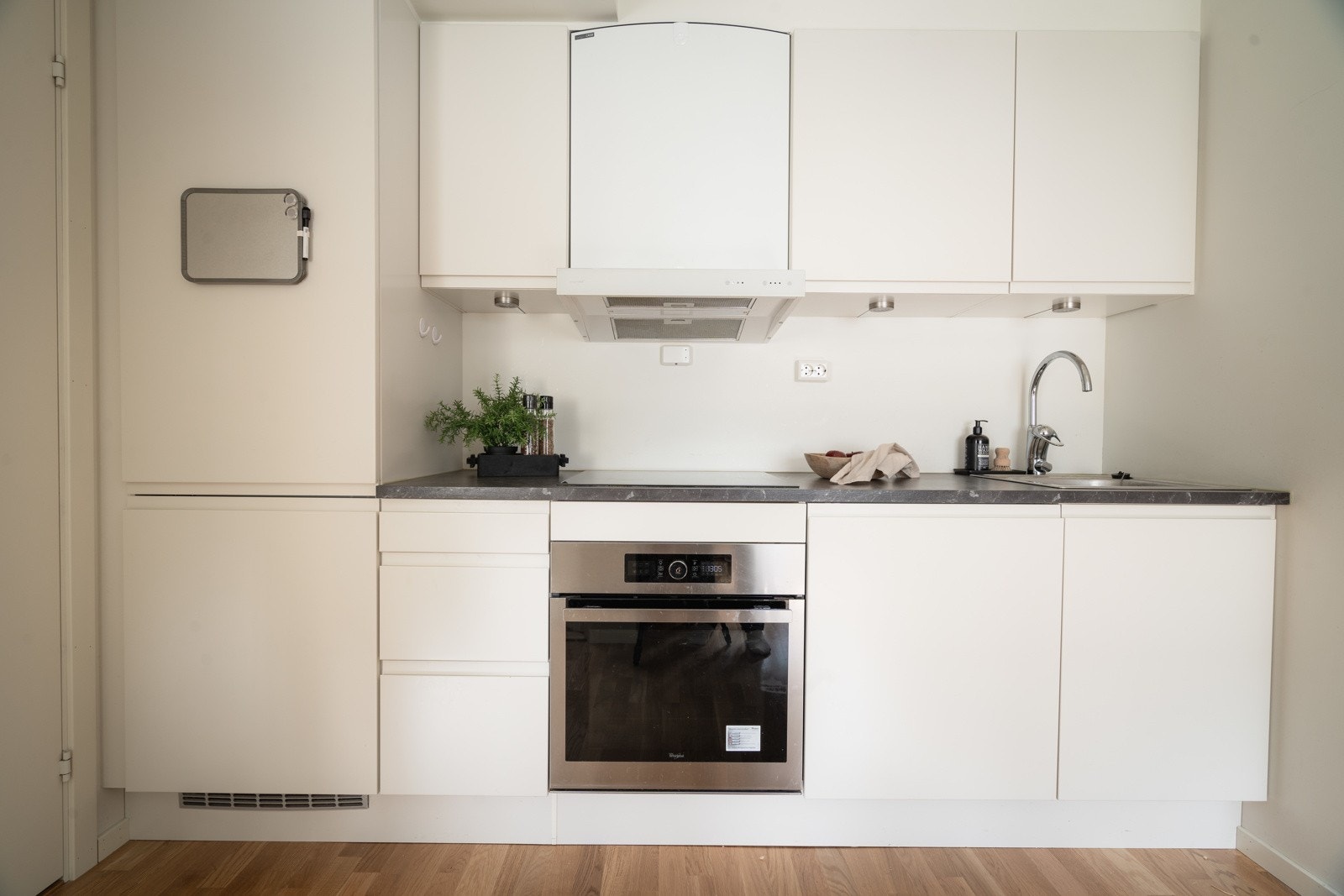 Tidløst kjøkken med hvite slette fronter og intergrerte hvitevarer. Åpen stue- og kjøkkenløsning med plass til spisebord i tilknytning til kjøkkenet. Galleribilde