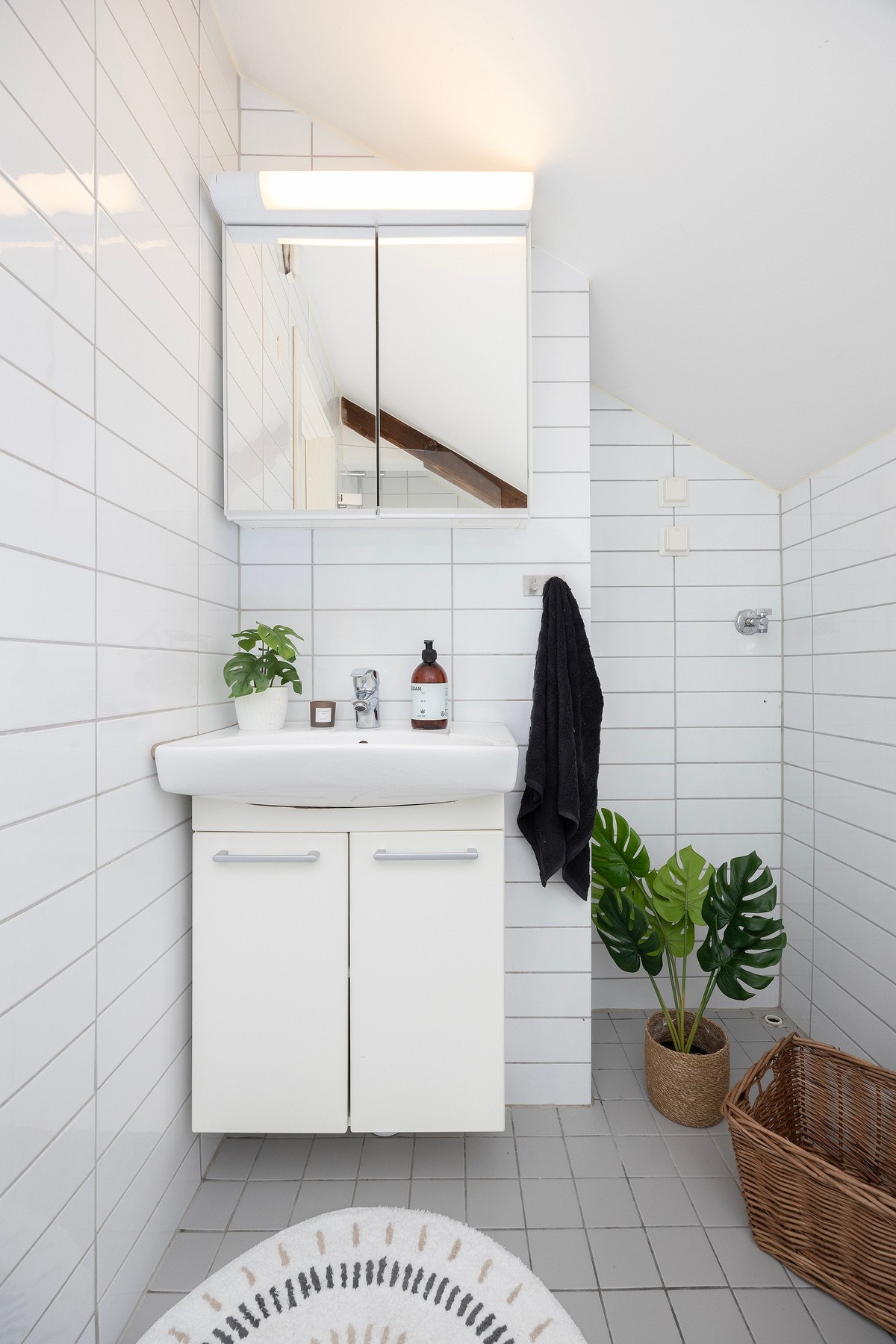 Servantskap med hvite fronter, veggskap med speilfronter og opplegg for vaskemaskin. Galleribilde