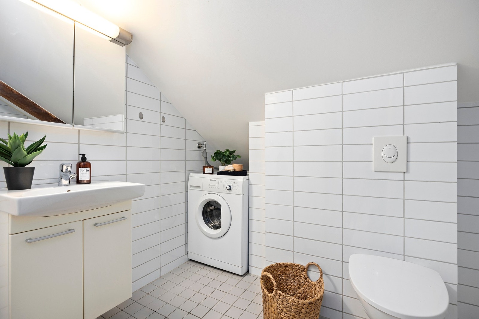 Flislagte flater, malt himling, servantskap, veggskap med speilfronter og opplegg for vaskemaskin. Galleribilde