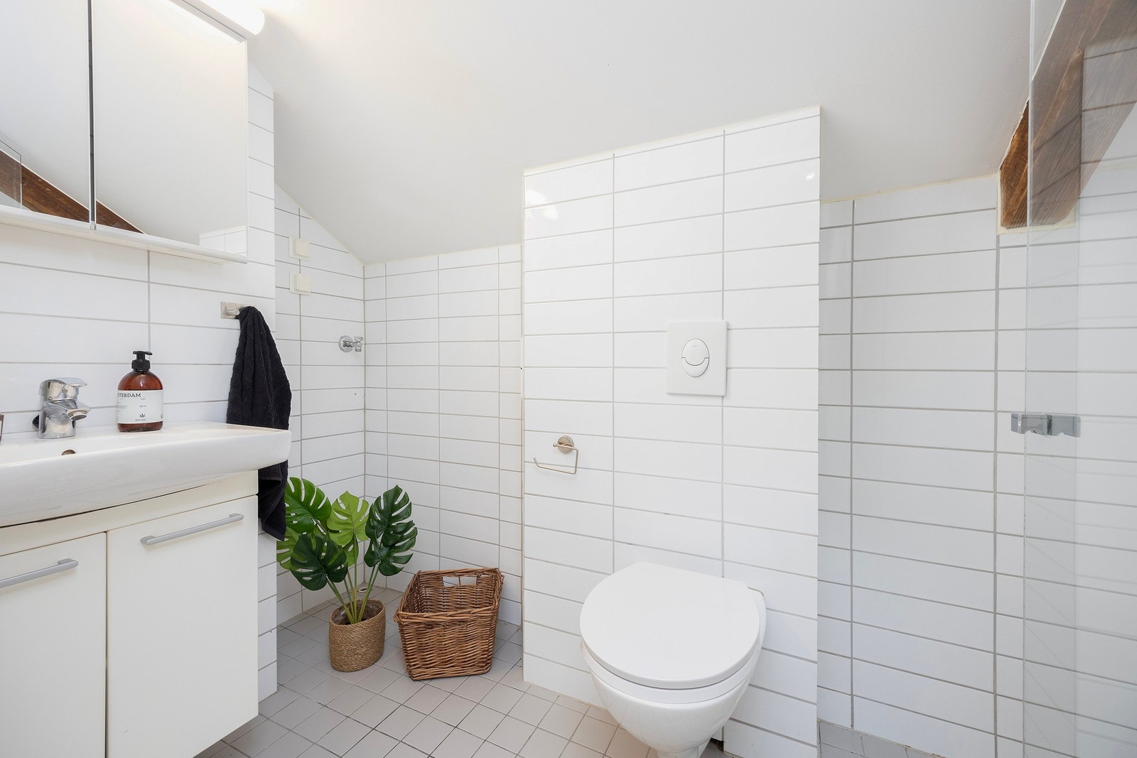 Leiligheten har tilsammen 2 bad og ett separat wc. Her er bad nr 2 med vegghengt wc, servant, skap og flislagte flater. Galleribilde