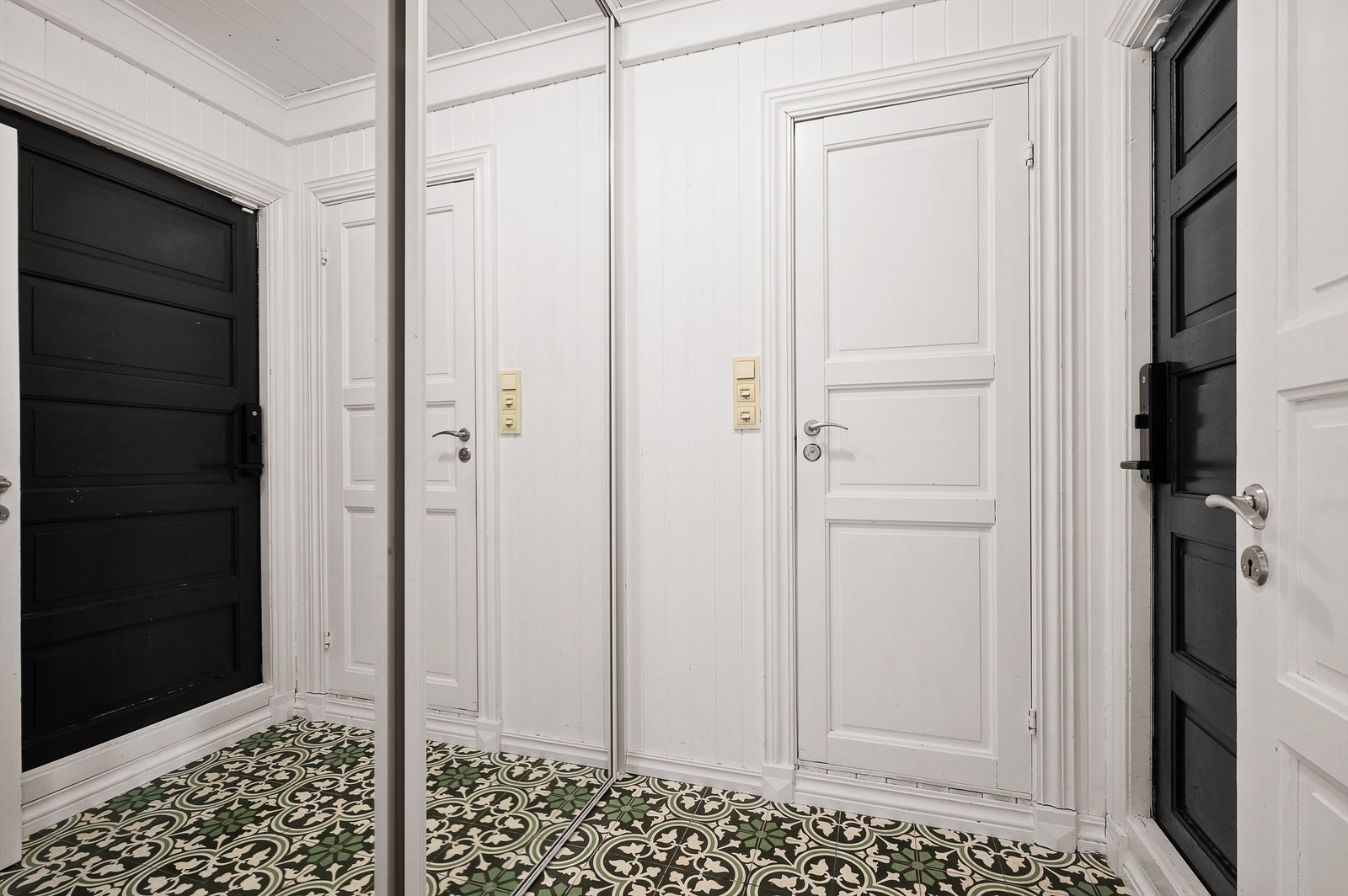 Gangen med historiske flis på gulvet og praktisk skyvedørsgarderobe. Galleribilde
