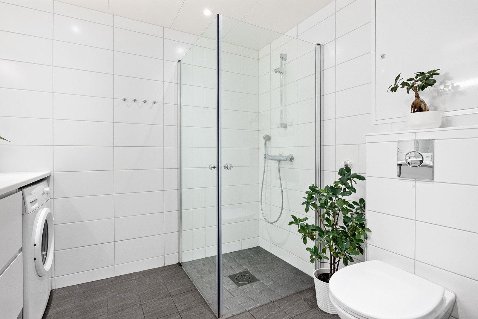 Vegghengt klosett og dusjhjørne med glassdører og to-greps armatur. Galleribilde