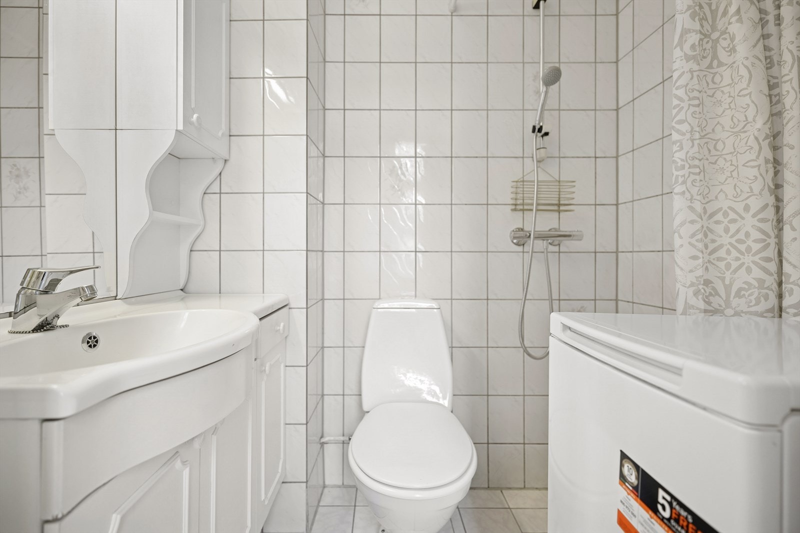 Badet er utstyrt med toalett, dusj med forheng, baderomsinnredning med servant, samt opplegg for vaskemaskin. Galleribilde